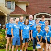 Alumni pose in front of the Alumni House